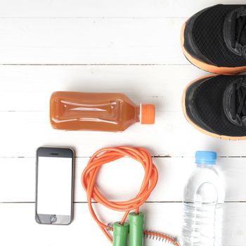 fitness equipment : running shoes,jumping rope,water,juice and phone on white wood background