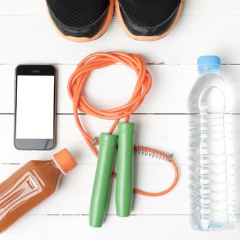fitness equipment : running shoes,jumping rope,water,juice and phone on white wood background