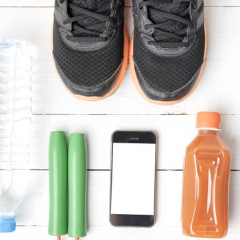 fitness equipment : running shoes,jumping rope,water,juice and phone on white wood background