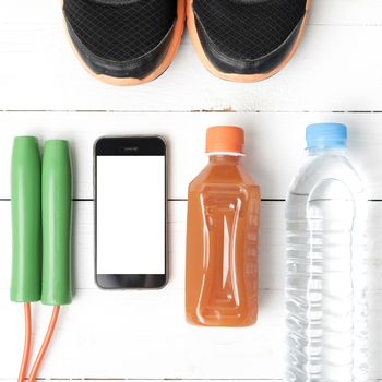 fitness equipment : running shoes,jumping rope,water,juice and phone on white wood background