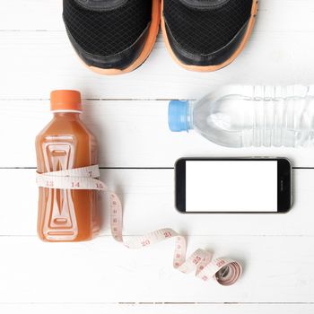 fitness equipment:running shoes,measuring tape,water,juice and phone on white wood background