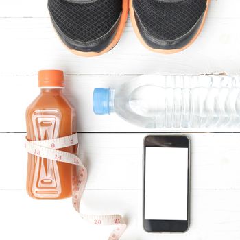 fitness equipment:running shoes,measuring tape,water,juice and phone on white wood background