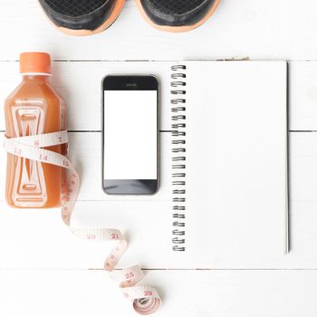 fitness equipment:running shoes,juice,measuring tape,notepad and phone on white wood background