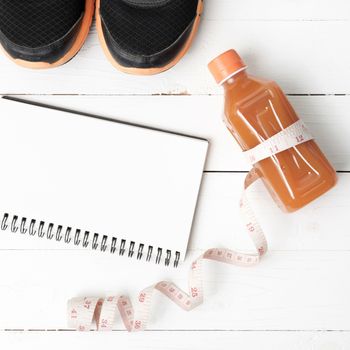 fitness equipment:running shoes,juice,measuring tape,notepad and phone on white wood background