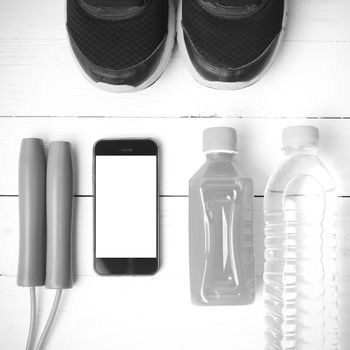 fitness equipment : running shoes,jumping rope,water,juice and phone on white wood background black and white color