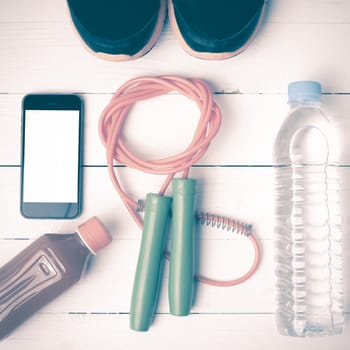 fitness equipment : running shoes,jumping rope,water,juice and phone on white wood background vintage style