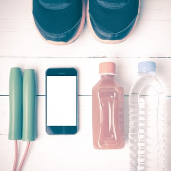 fitness equipment : running shoes,jumping rope,water,juice and phone on white wood background vintage style