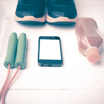 fitness equipment : running shoes,jumping rope,water,juice and phone on white wood background vintage style