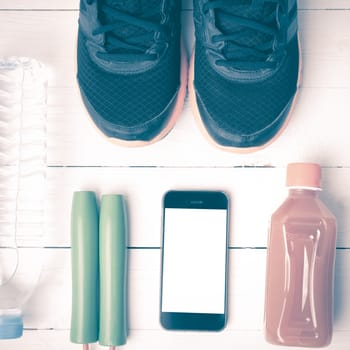 fitness equipment : running shoes,jumping rope,water,juice and phone on white wood background vintage style