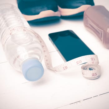 fitness equipment:running shoes,measuring tape,water,juice and phone on white wood background vintage style