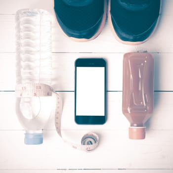 fitness equipment:running shoes,measuring tape,water,juice and phone on white wood background vintage style