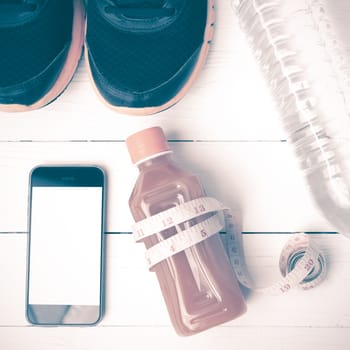 fitness equipment:running shoes,measuring tape,water,juice and phone on white wood background vintage style