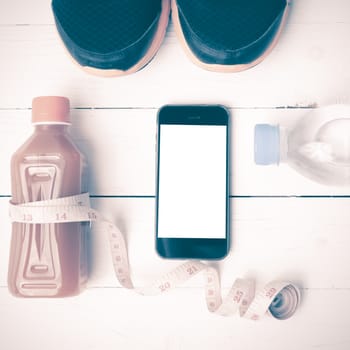 fitness equipment:running shoes,measuring tape,water,juice and phone on white wood background vintage style