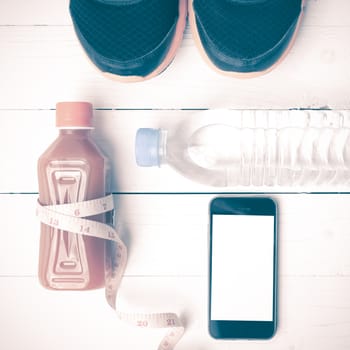 fitness equipment:running shoes,measuring tape,water,juice and phone on white wood background vintage style