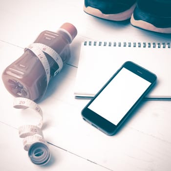 fitness equipment:running shoes,juice,measuring tape,notepad and phone on white wood background vintage style