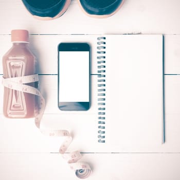 fitness equipment:running shoes,juice,measuring tape,notepad and phone on white wood background vintage style