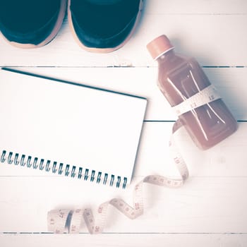 fitness equipment:running shoes,juice,measuring tape,notepad and phone on white wood background vintage style