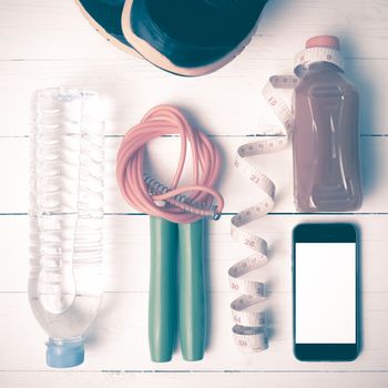 fitness equipment:running shoes,phone,measuring tape,water,juice and jumpong rope on white wood background vintage style