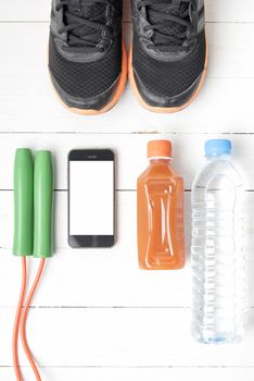 fitness equipment : running shoes,jumping rope,water,juice and phone on white wood background