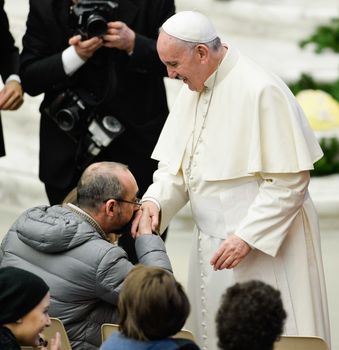 CITE DU VATICAN, Vatican City : A man kisses the hand of Pope Francis during his weekly general audience on January 13, 2016 in Paul VII hall at the Vatican.