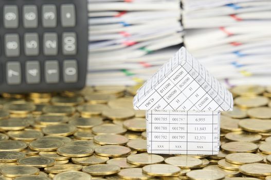 Close up house on stack of gold coins have blur calculator place vertical and pile of document as background.