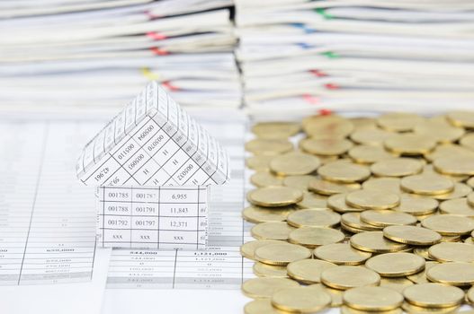 House with stack of gold coins on another side on finance account have blur pile of document as background.