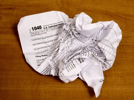 Crumpled up tax form from frustration.  On a wood background.