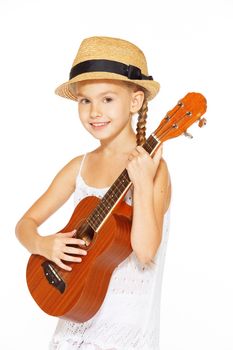 A beautiful little girl with a charming smile in a white dress with a guitar
