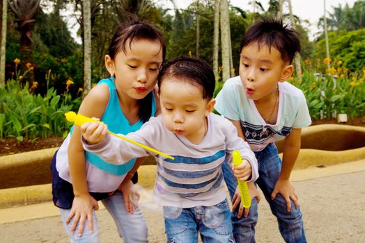 Asian kids blowing bubbles outdoor