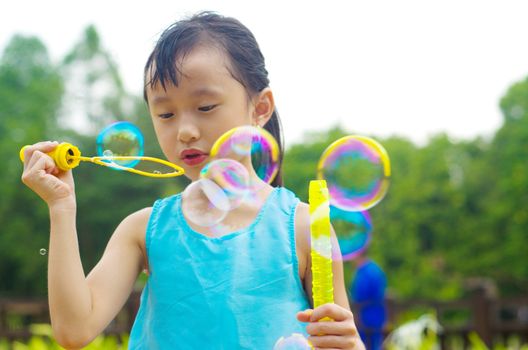 Asian girl blowing bubbles outdoor