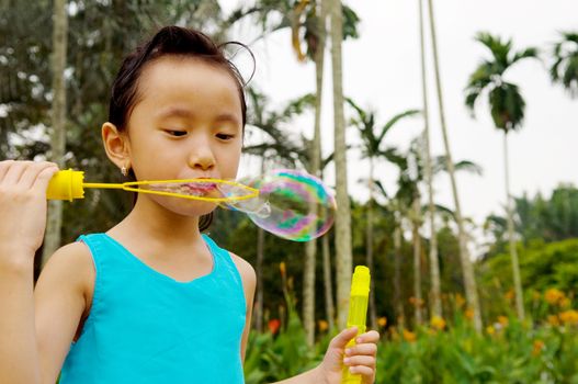 Asian girl blowing bubbles outdoor