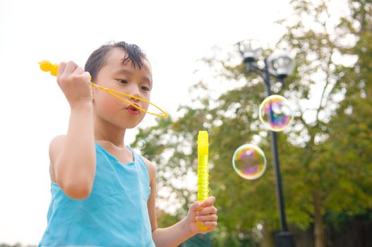 Asian girl blowing bubbles outdoor