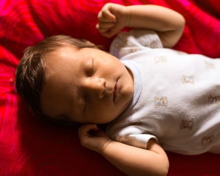 Newborn boy sleeping peacefully on a red background