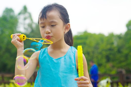 Asian girl blowing bubbles outdoor