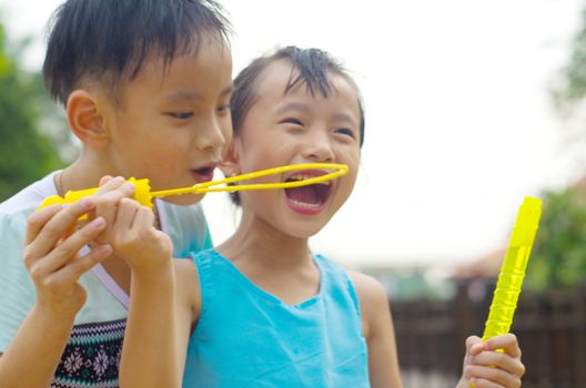 Asian kids blowing bubbles outdoor