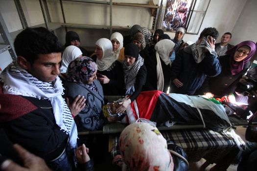 WEST BANK, Bethlehem: The mother of a Palestinian man identified as Srur Ahmad Abu Srur and who was shot and killed during clashes with Israeli security forces, looks down at his son's corpse during the funeral ceremony at Aida refugee camp in Bethlehem, West Bank on January 13, 2016.The corpse was buried at Aida refugee camp a day after the Palestinian man was allegedly shot in the chest by Israeli forces in Beit Jala, a Palestinian health ministry statement said. 