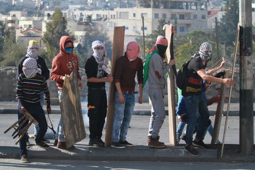 WEST BANK, Bethlehem: Palestinian protesters hide themselves behind pieces of wood during clashes with Israeli security forces in the West Bank town of Bethlehem following a funeral ceremony at the nearby Aida refugee camp on January 13, 2016. A Palestinian man identified as Srur Ahmad Abu Srur, 21, was buried at Aida refugee camp a day after he was allegedly shot in the chest by Israeli forces in Beit Jala, a Palestinian health ministry statement said. 