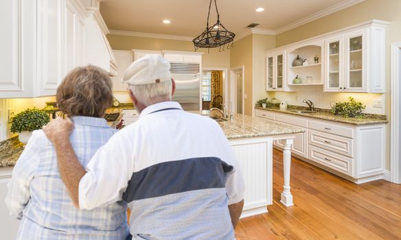 Happy Senior Couple Looking Over Beautiful Custom Kitchen Design.