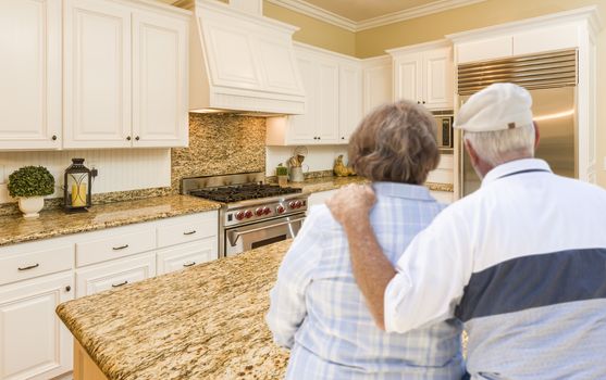 Happy Senior Couple Looking Over Beautiful Custom Kitchen Design.