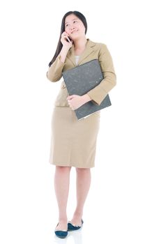 Business Women holding file standing while talking on mobile phone isolated over white background.