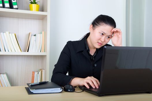 Headache Asian business woman holding her head, working with laktop