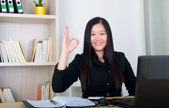 confident young business woman, showing ok sign , working in the office.