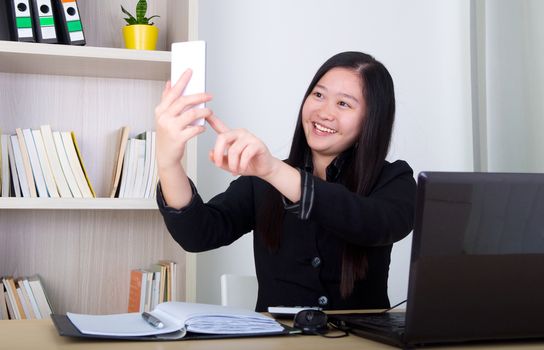 smiling young business woman working with smart phone and laptop 