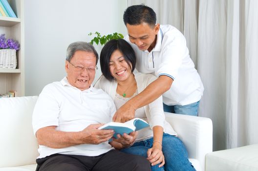 Asian family reading book at home