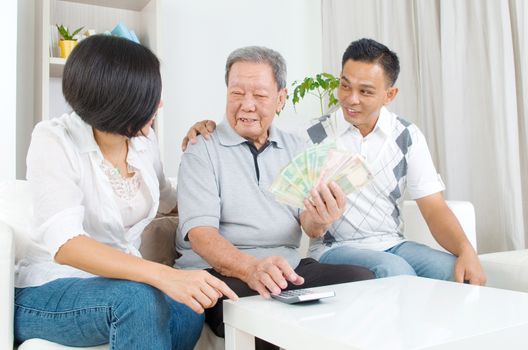 Asian senior man and children calculating money at their home