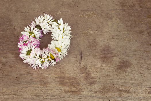 Small wreath of daisies on old wooden table