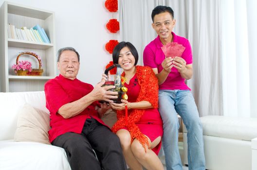 Asian childrern presenting gift basket and red packet to parent on chinese new year