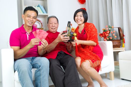 Asian childrern presenting gift basket and red packet to parent on chinese new year