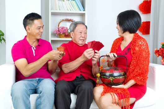 Asian childrern presenting gift basket and red packet to parent on chinese new year