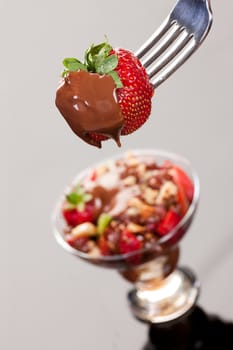 Strawberry in chocolate on a fork on isolated background